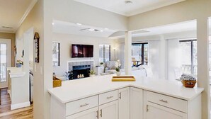 Una cocina moderna con armarios blancos, horno integrado y un ventanal que proporciona luz natural.