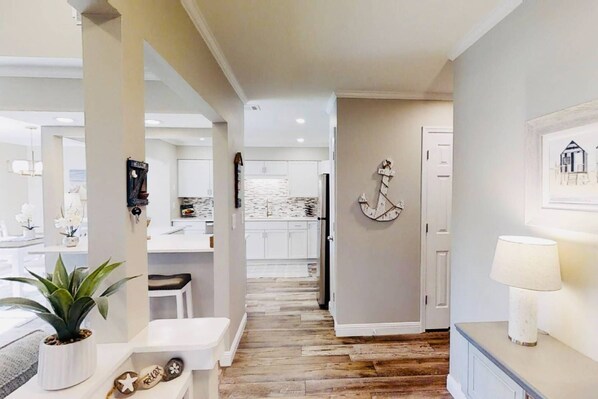 A modern kitchen with white cabinets, a wooden floor, and a view into the dining area. - Best Location-Shipyard, Walk to Beach, Updated, Private Deck, Pool, Golf & Tennis, Guest Favorite (Hilton Head Island)