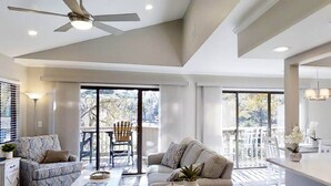 Una amplia sala de estar con ventilador de techo, un sofá, una mesa de centro y un comedor con mesa y sillas.