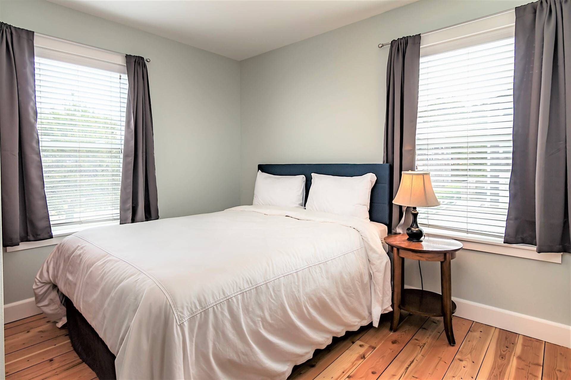 A bedroom with a large bed, two bedside tables, and a window with curtains.