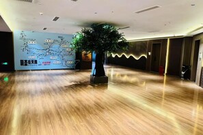 A spacious lobby with a polished wooden floor, a large tree sculpture, and a wall with a map. - Naqu Zangdi Tianxiang Hotel (Nagqu)