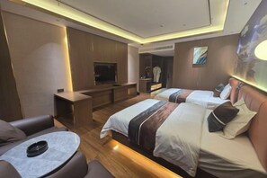 Una habitación de hotel moderna con dos camas, televisión, zona de estar con mesa y armario.