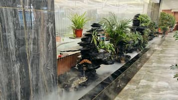 A lobby with a water feature, marble columns, and potted plants.