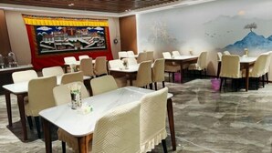 A dining area with multiple tables and chairs, a mural on the wall, and a tiled floor. - Naqu Zangdi Tianxiang Hotel (Nagqu)