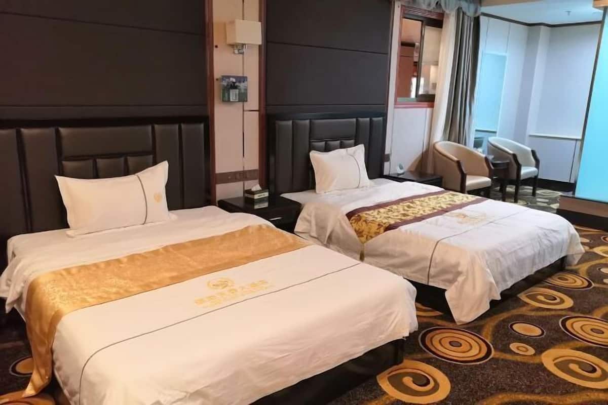 A hotel room with two beds, a large window, and a seating area.