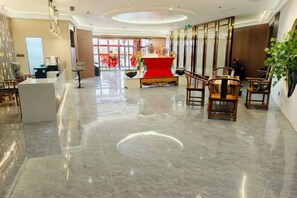 A hotel lobby with a reception desk, seating area, and a decorative centerpiece.