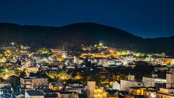 A densely packed urban area with traditional and modern buildings, a prominent pagoda, and a mountainous backdrop.