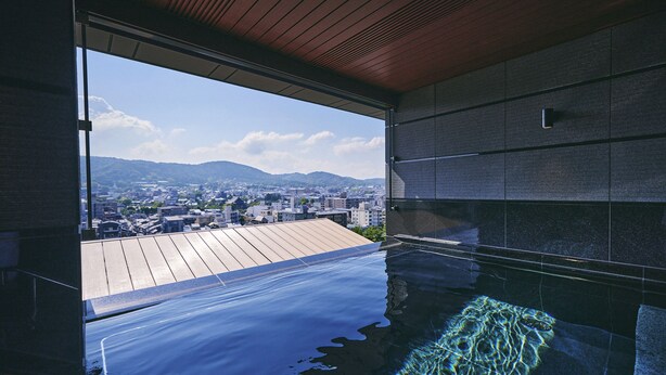 Piscina interior moderna con vista a un paisaje urbano y montañas.