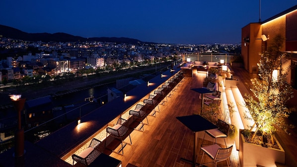 Enjoy panoramic city views from this rooftop terrace, featuring comfortable seating areas and a dining table.
