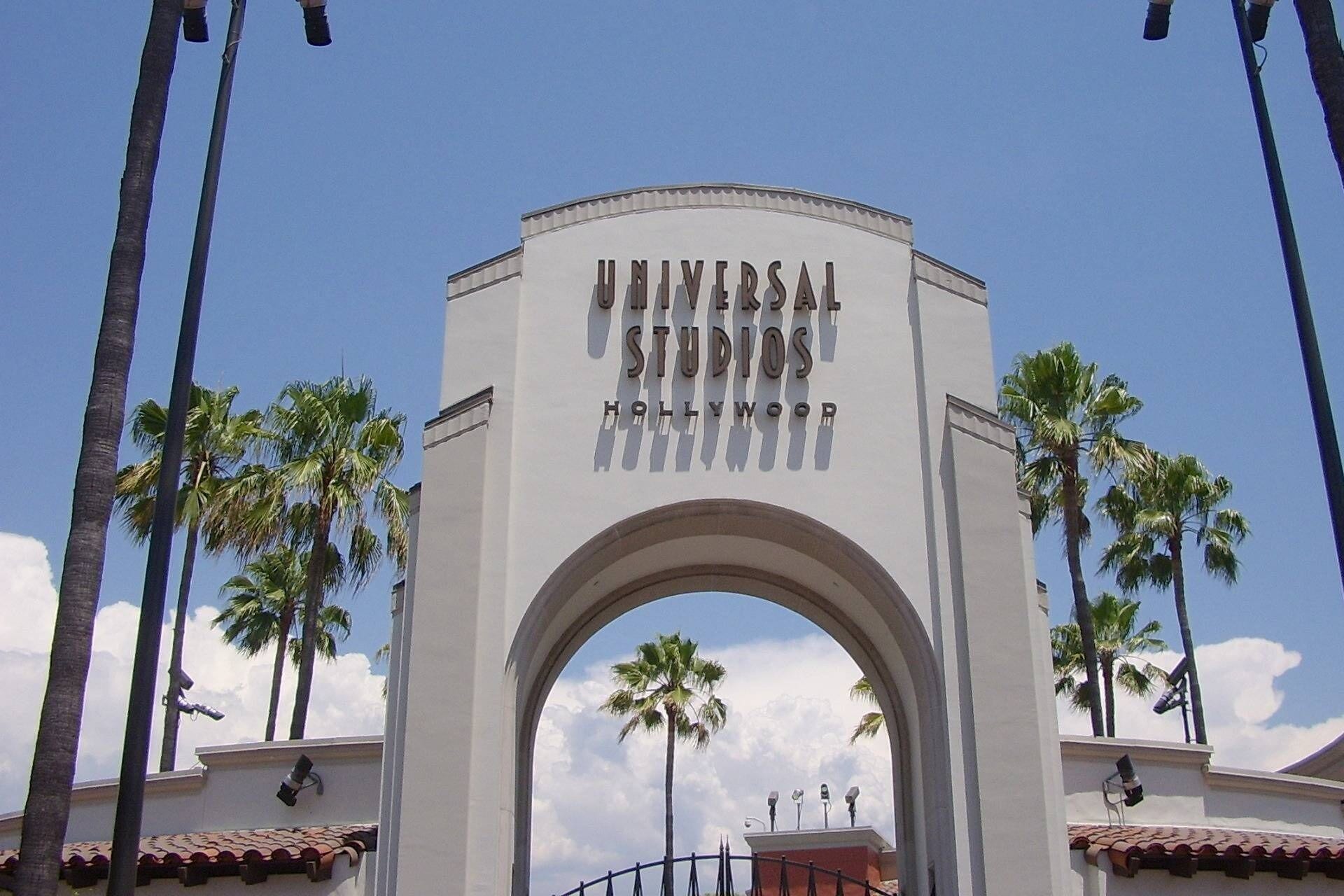 An archway with "Universal Studios Hollywood" written on it, surrounded by palm trees.