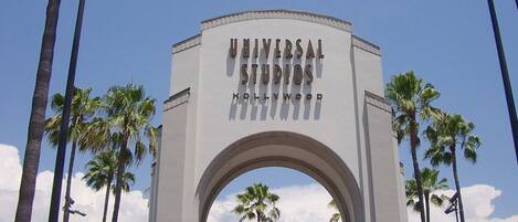 An archway with "Universal Studios Hollywood" written on it, surrounded by palm trees.