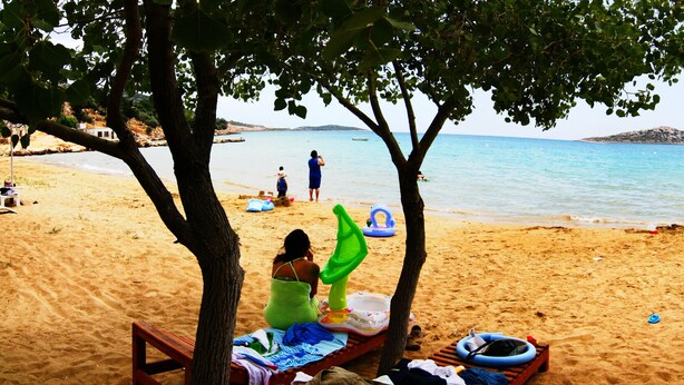 Una platja amb ombrelles, gandules i gent gaudint de l'aigua.