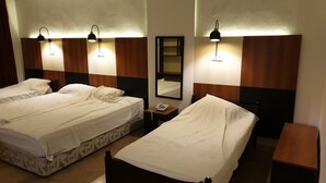 A hotel room with two beds, a bedside table with a phone, and wall-mounted lamps.