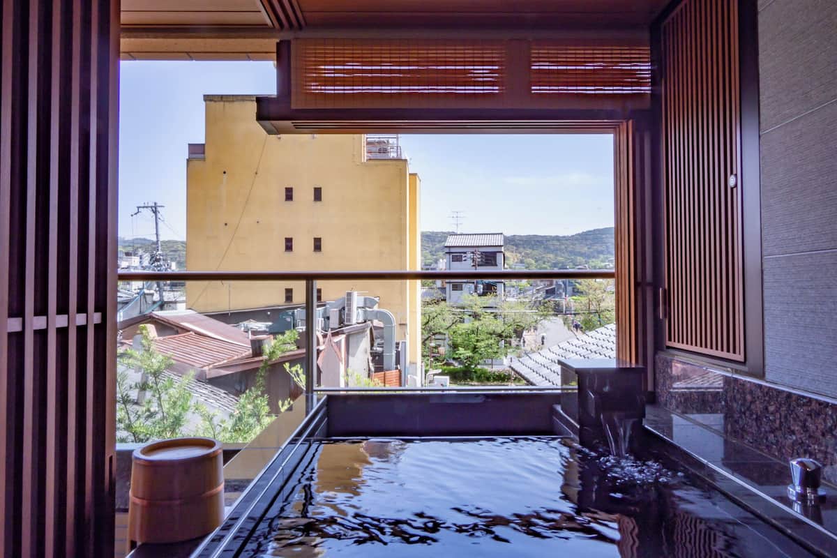 Une chambre avec vue sur la ville, une baignoire et un plancher en bois.