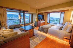 A hotel room with a sofa, a bed, a desk, and a TV. The room has large windows with a view of a city and mountains. - Sora Niwa Teracce Kyoto Bettei (Kyoto)