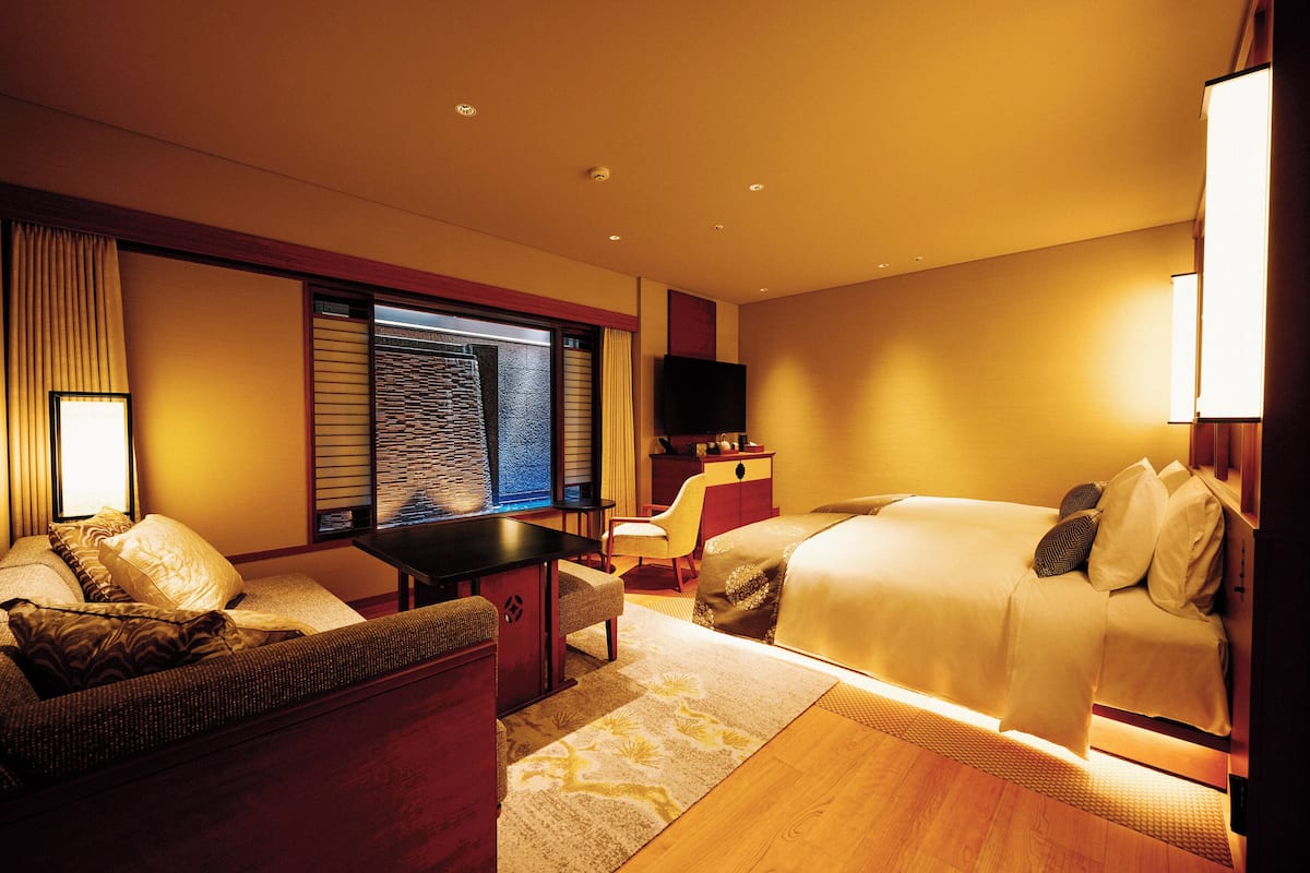 Une chambre d’hôtel avec un lit, un canapé, un bureau et une télévision.