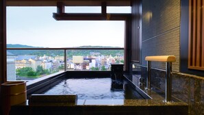 A hot tub with a city view, a wooden bench, and a stone ledge. - Soraniwa Terrace Kyoto Bettei (Kyoto)