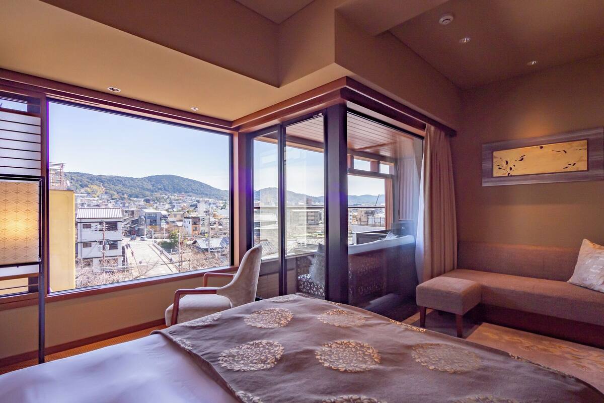 Une chambre d’hôtel dotée d’un grand lit, d’un coin salon et d’un balcon offrant une vue sur la ville.