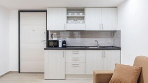 Una cocina moderna con armarios blancos, un microondas, un hervidor y un lavabo.