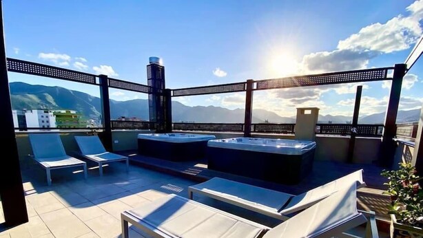 Una terraza en la azotea con sillones, un jacuzzi y vistas a las montañas.