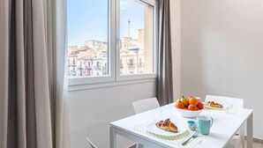 Un comedor con una mesa preparada para el desayuno, un cuenco de fruta y un croissant.