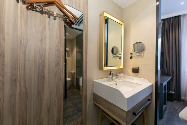 A modern bathroom with a wooden vanity, a large mirror, and a shower area. - Hanting Hotel (Shanghai)