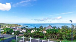 A coastal residential area with houses, a beach, and a clear blue sky. - Océanides - Renovated studio with magnificent sea view (Saint-Paul)