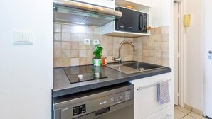 A modern kitchen with a built-in microwave, stainless steel sink, and a dishwashing unit. - Océanides - Renovated studio with magnificent sea view (Saint-Paul)