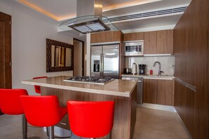 Eine moderne Küche mit einer zentralen Kochinsel, roten Barhocker, Edelstahlgeräten und Holzschränken.