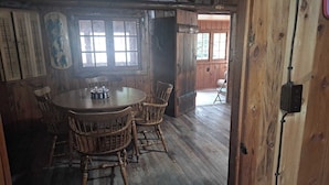 A rustic wooden dining room with a round table and four chairs.