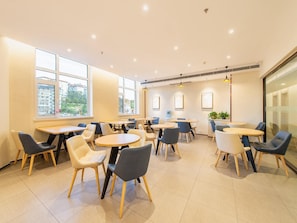 Un café moderne avec des tables et des chaises rondes, de grandes fenêtres et un intérieur propre et lumineux.
