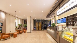 A modern coffee shop interior with wooden flooring, seating areas, and a counter with a coffee machine and display of beverages. - Hanting Hotel (Dalian)
