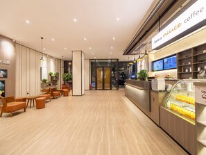 Un interno di caffetteria moderna con pavimento in legno, aree salotto e un bancone con macchina da caffè ed esposizione di bevande.
