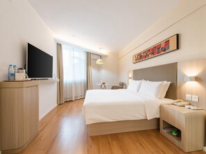A hotel room with a bed, bedside table, lamp, and a television. - Hanting Hotel (Dalian)