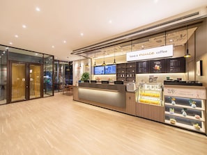 A modern coffee shop interior with a reception desk, seating area, and a menu board. - Hanting Hotel (Dalian)