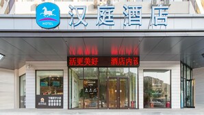 L’entrée d’un hôtel, avec une enseigne indiquant « 汉庭酒店 » et un panneau lumineux au-dessus portant l’inscription « 活更美好 酒店内设 ».