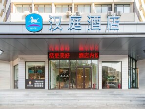 L’entrée d’un hôtel, avec une enseigne indiquant « 汉庭酒店 » et un panneau lumineux au-dessus portant l’inscription « 活更美好 酒店内设 ».