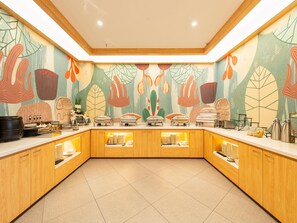 Une cuisine moderne avec des meubles en bois, un îlot central servant de buffet pour présenter les plats, et une fresque murale abstraite et colorée.