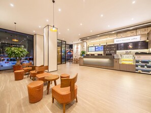Un interno di una caffetteria moderna con arredi in legno e una vetrina digitale per il menù.