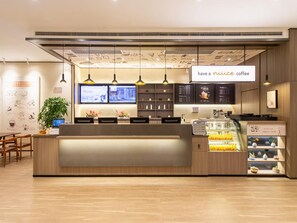 A coffee shop interior with a reception desk, digital menu boards, and a coffee display. - Hanting Hotel (Dalian)
