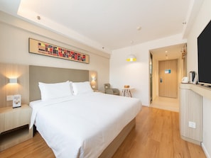 A hotel room with a large bed, bedside tables, a desk, a chair, a small table with a lamp, and a painting on the wall. - Hanting Hotel (Dalian)