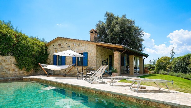 A stone villa with a swimming pool, outdoor seating, and a garden.