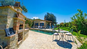 A stone pool with outdoor seating and a stone wall.