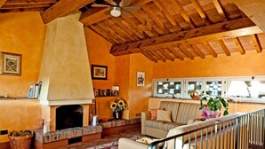 A cozy living room with a fireplace, a ceiling fan, and a staircase. - SOTTO COLLE - COTTAGE (Montelupo Fiorentino)