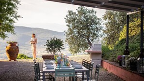 An outdoor dining area with a table and chairs, a potted plant, and a stone statue. - Villa with pool in splendid panoramic location, just 20 minutes from Florence (Montelupo Fiorentino)