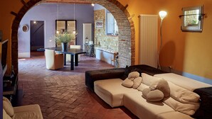 A cozy living area with a sofa, a dining table, and a stone wall. - Villa with pool in splendid panoramic location, just 20 minutes from Florence (Montelupo Fiorentino)