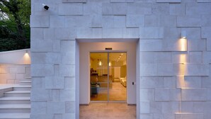 A modern building entrance with a glass door, a staircase leading up, and exterior lighting. - Larimar (Becici)