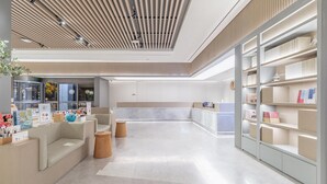 A modern interior with a reception desk, seating area, and bookshelves. - JI Hotel (Nanjing)