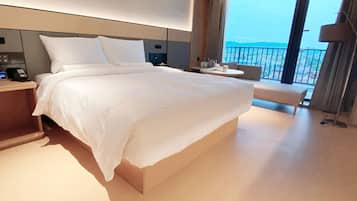 A modern hotel room with a large bed, bedside table, and a view of the city through the balcony.