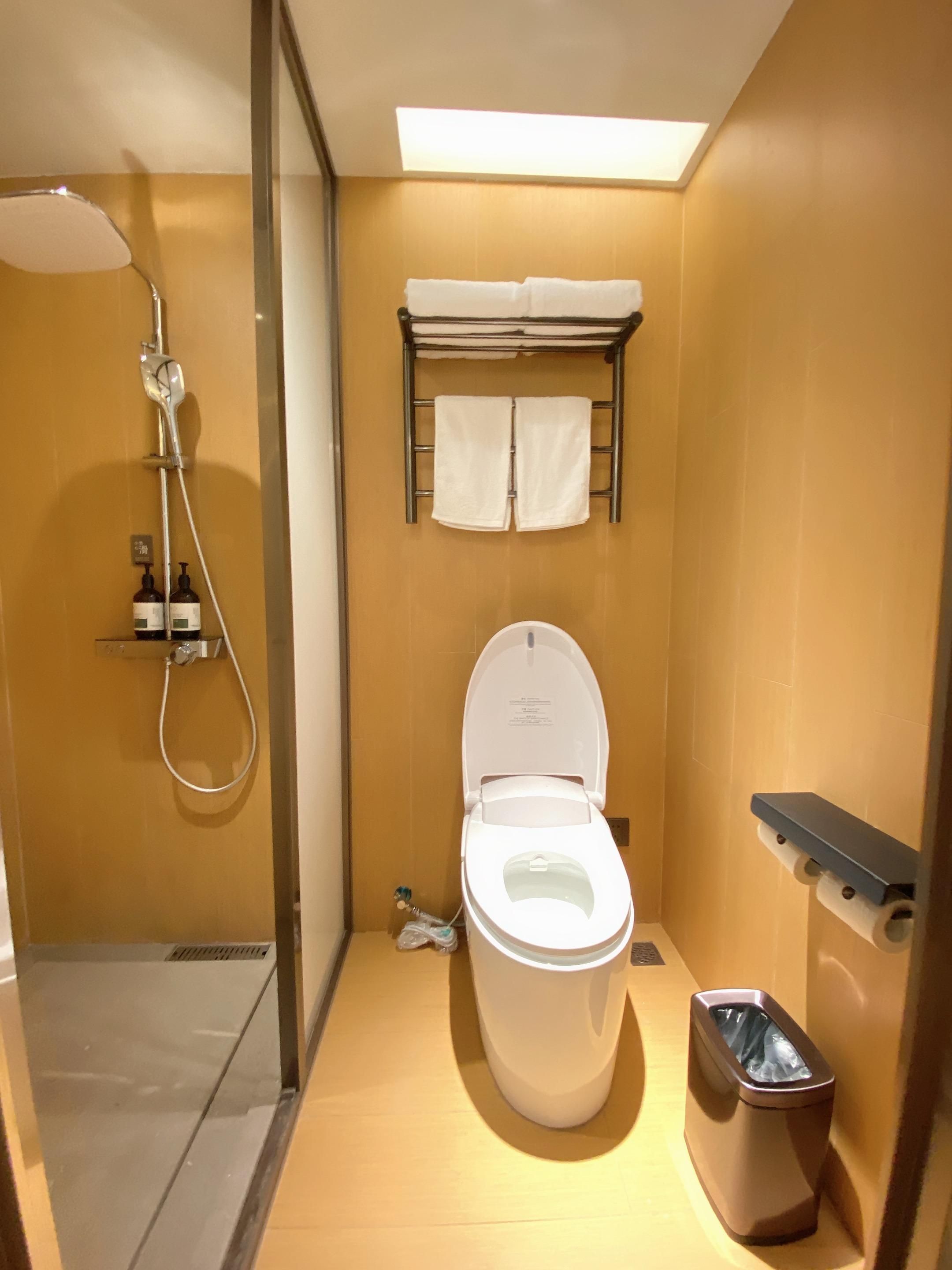 Un baño pequeño con ducha, inodoro y un cubo de basura.